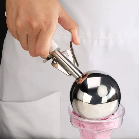 Hand using Thumb-Press Food Disher Ice Cream Scoop 4.67 Oz Size 6 White, 18/8 Stainless Steel, for portioning ice cream.