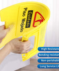 Close-up of a person folding a yellow durable plastic Wet Floor Sign Caution Foldable Double Sided Bilingual For Commercial Use