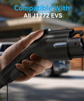 Hand holding J1772 Compatible Level 2 EV Wall Charger For 240V 40A With 25Ft Cable And NEMA 14 50 Plug, vehicle in background