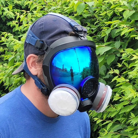 Side view of person wearing Dope Full Face Respirator Mask for wildfire smoke, with eye protection and dual filter, reflecting surroundings.