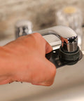 Hand using Easy Peasy Multi Use Faucet Aerator Key Tool For Scratch Free Removal And Installation Fits Most Standard Nickel And Tiny Aerators Works On Most Brands Durable Black Handle on chrome faucet