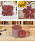 Pro Grade 150 Pack Round Sanding Discs 5 Inch Hook And Loop Replacement Pads shown stacked on a wooden surface for DIY projects.