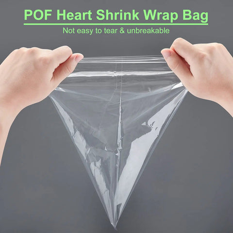 Hands holding a clear POF heart shrink wrap bag, showcasing its durability and flexibility for packaging.