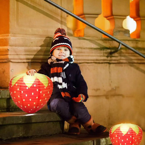 Child holding Strawberry Paper Lanterns Set Of 4 Large 8 Inch And 12 Inch Hanging Decor 3D Red Strawberry Party Lanterns on steps