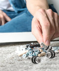 Hand holds heavy duty shelf support pegs with self tapping screws for cabinets and wood shelving, 20 piece set on carpet.