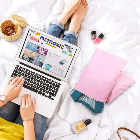 Person using laptop next to light pink 10x13 poly mailers 100 pack waterproof shipping envelopes for clothing strong adhesive bags
