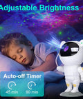 Child sleeping under Nebula Night Light Projector For Kids With 8 Nebula Effects And Green Twinkling Stars, astronaut design