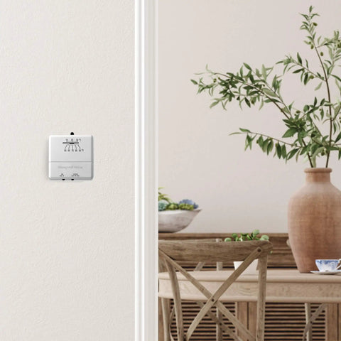 CT30A1005 Heat Only Manual Economy Thermostat Almond Finish 0.6 In low voltage control on wall in cozy room setting.
