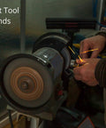 Person using a bench grinder tool with sparks flying, focusing on hands and grinding wheel in a workshop setting.