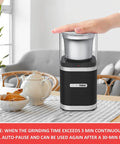 Electric Coffee Bean Grinder With Slick One Touch Operation And 180W Motor Brewing Fresh Espresso Right Quick With A Removable Stainless Bowl For 12 Cups And Brush In Sleek Black on a kitchen counter with flowers.
