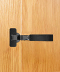 Side view of a Slick Soft Close Concealed Cabinet Door Hinge With Silent Damping For Kitchen Cabinets, black, installed on wood.
