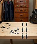 GoTo 12-Piece Black Zipper Puller Repair Kit With Detachable Sliders on wooden table with backpack and jacket closet in background