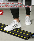 Person stepping over 6 Ft Floor Cable Cover With Three Large Cord Channels For Wires On The Floor Beefy Heavy Duty PVC Duct Black