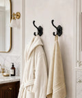 Solid Build Vintage Black Wall Hooks Heavy Duty Coat And Towel Rack Four Pack holding a white robe and towel in a bathroom.