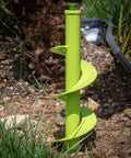 Rapid Planting Bulb Auger Drill Bit 3.5 X 12 Inches lime green tool in garden, inserted in soil near plants and hose.