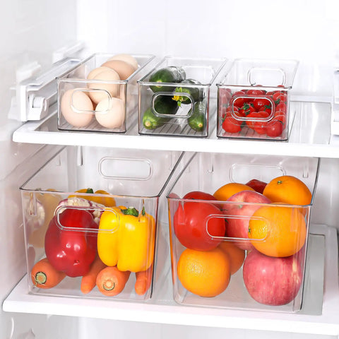Total Game Changer Clear Plastic Storage Bins Eight Pack Of See Through Pantry Organizers And Fridge Containers arranged in a refrigerator with fruits and vegetables.