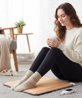 Woman enjoying a cup of coffee sitting on Cozy Foot Warmer Heated Floor Mat With 110V PVC Design 10 Temperature Settings, under desk.