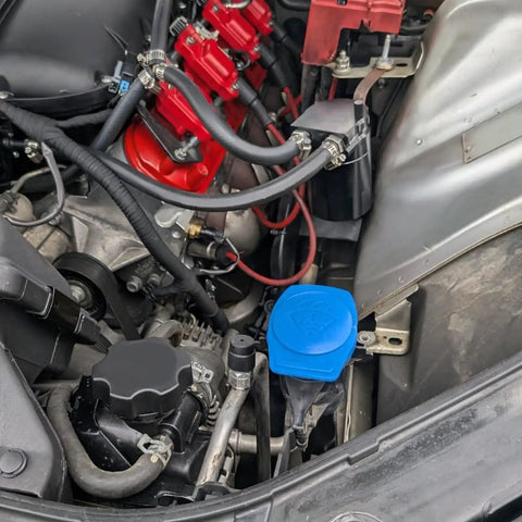 Porsche Cayenne Windshield Washer Fluid Cap Replacement 3Q0955455 installed under vehicle hood, with blue reservoir cap
