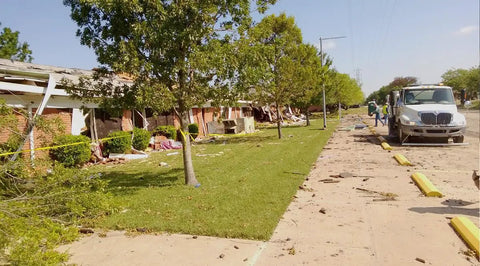 Scene of damaged buildings with debris on the ground, indicating a recent cleanup after a disaster.