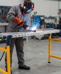 Person welding on a Rugged Alloy Steel Folding Welding Table With Four Thousand Pounds Capacity with sparks flying.