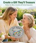 Mother and daughter holding a personalized DIY stepping stone with mosaic tiles and 'My Mom' text, in a garden setting.