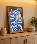 Framed Coastal Kayaking Wall Art Ocean Decor Poster Abstract Wave Print Rowing Artwork leaning on a shelf in a cozy room.