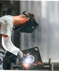 Heavy Duty Aluminum Foil High Heat Resistant Arm Sleeves Sweat Free Adjustable Breathable Guard Shields For Mechanics Hot Shop Work Lab Safety And Backyard Grills worn by a welder, shielding arm from sparks.