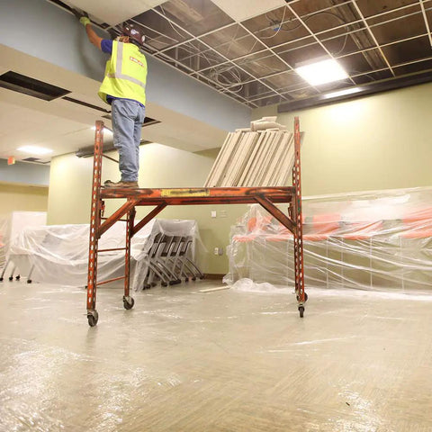 Construction worker on scaffold in room with Heavy Duty Carpet Shield Film 36 Inch By 500 Feet 2 Mil Tear Resistant Masking Film