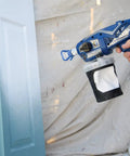 Cordless Handheld Paint Sprayer Generates Slick Airless Finishes Without Thinning, aimed at a partially painted door.
