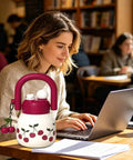 Person using laptop in cafe with a decorative water bottle featuring cherries