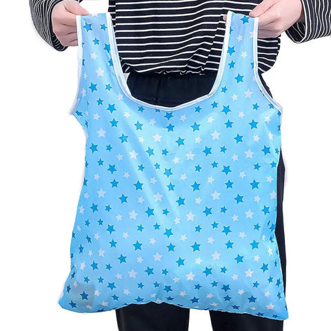 Person holding a blue star-patterned foldable reusable grocery tote bag, lightweight 190T polyester, waterproof, six pack eco-friendly carrier.