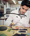 Man using 5X Rechargeable Magnifying Glass With Light And Stand For Reading And Close Work Handy Dimmable LED Desk Magnifier while repairing circuits.