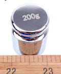 Pro Grade 200 Gram Steel Calibration Weight M1 Class For Scales And Jewelry Balances, Lab Grade Calibration Weight With Plus Minus 10 Mg Tolerance next to ruler.