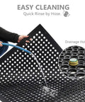 Image of a Drainage Rubber Floor Mat With Holes Keeps Wet Areas Dry Heavy Duty Anti Fatigue Non Slip being rinsed with a hose.