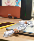 Leather Cord Organizer And Cable Keeper Case For Earbuds And Headphones on desk with light brown leather ties and cables