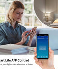 Woman using phone with app for 2 Gang Glass Panel WiFi Smart Light Switch With Touch Control; lamp controlled remotely.