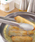 Two Pack 9 Inch And 12 Inch Stainless Steel Kitchen Tongs With Locking Mechanism in use, lifting food from frying pan