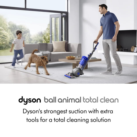 Dyson Ball Animal Total Clean upright vacuum cleaner in blue and gray, shown in a living room with a dog nearby.