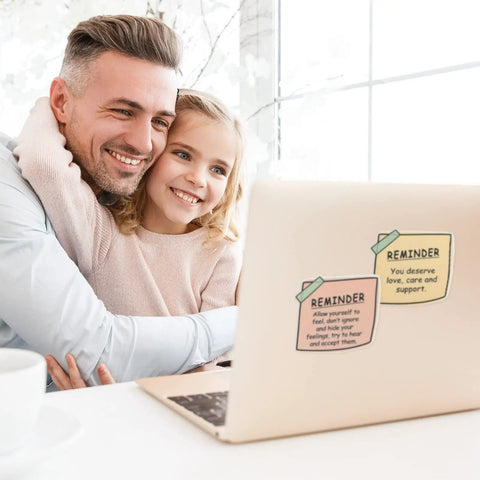 Father and daughter with laptop displaying 24 Pcs Mental Health Stickers Set With 8 Styles, Motivational Affirmations, Waterproof