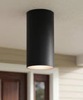 Sleek Six Inch Cylinder Outdoor Ceiling Light, black aluminum, shown mounted on porch ceiling. Modern, minimalist, damp-rated design.