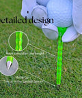 Close-up of Forever Tee Premium Metal Unbreakable Golf Tee with green plastic wrap and extended metal tip, held by gloved hand on grass.
