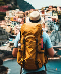 Traveler with a backpack holding a Portable Metal Toothpick Holder Case With Keychain Waterproof Aluminum Alloy in a scenic village