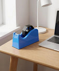 Portable Plastic Tape Dispenser With Weighted Non Slip Base And Vertical Roll Mechanism, Quick Release Blade, Desk Side Organizer For Washi And Masking Tapes, Great For Office, School, And Stationery Setups on wooden desk beside laptop