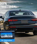 Rear view of a black car with Rear License Plate Bracket Holder Fits Audi A3 A4 A5 A6 A7 A8 S4 S5 S6 S7 RS5 RS6 RS7 Q3 Q5 SQ5 2012-2025 With Screws And Wrench Tail Bumper Tag Frame Upgrade driving by the coast.