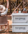 Heavy Duty Rolling Bin With Secure Lid And Easy Roll Casters, Stackable Outdoor Camp Organizer, outdoor scene with two white bins and a woman sitting.