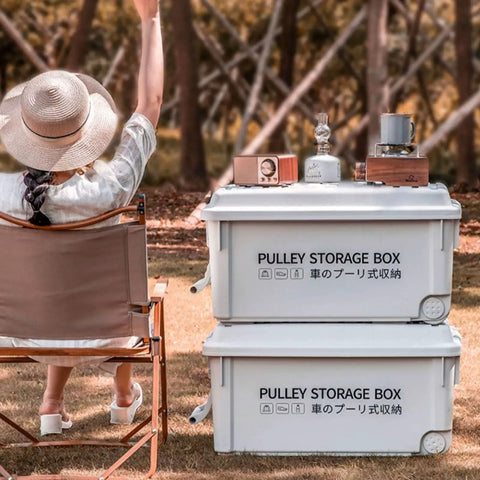 Heavy Duty Rolling Bin With Secure Lid And Easy Roll Casters, Stackable Outdoor Camp Organizer, outdoor scene with two white bins and a woman sitting.