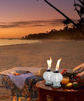 Four Pack Clear Glass Table Top Torches For Outdoors Mini Citronella Lanterns on beachside table at sunset