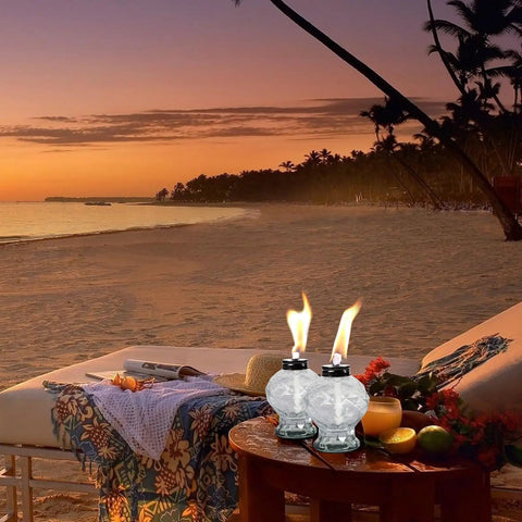 Four Pack Clear Glass Table Top Torches For Outdoors Mini Citronella Lanterns on beachside table at sunset