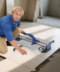 Man using 24 Inch Manual Tile Cutter With Tungsten Alloy Wheel And Guided Rail for precise ceramic cuts on the floor.