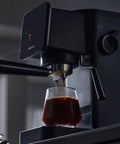 Badass Home Espresso Maker With Slick Touchscreen Interface And 20 Bar Pump Pulls Knockout Shots For Smooth Lattes Or Quick Cold Brew Featuring Full Milk Frothing Setup With Generous 41oz Water Tank brewing espresso into a glass.